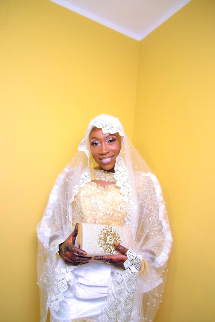 Stylish woman poses with a golden clutch and a luxurious white veil, exuding fashion and grace.